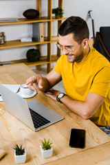 cheerful man pointing with finger at laptop at home
