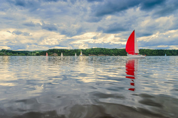 Sailing yacht in the morning, in the evening reflected in the water beautiful clouds of light.