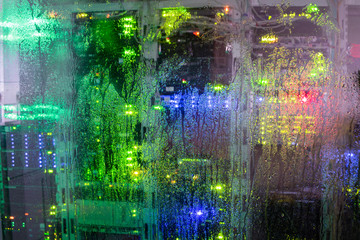 Drops of rain flow down the glass wall of the server room. Wet glass of the datacenter. Abstract background.