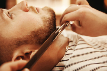 Client is male hipster caring for beard in barbershop. Shave hair