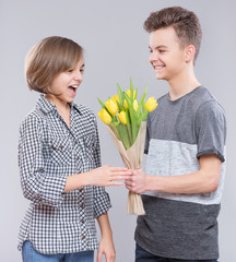 Boy Giving Tulips for Girl. Holidays, Love, Happiness and People concept - Happy Child celebrating Valentines Day. Teen Boy and Girl with Flowers. 