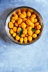 kumquat fruits on a   silver bowl on a gray concrete board,top view,natural light