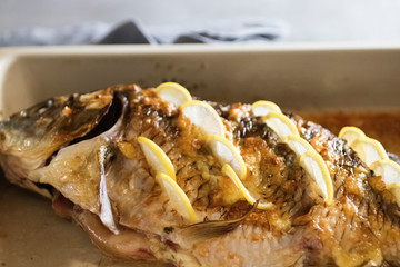 Whole baked carp with slices of lemon.