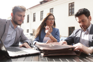 business partners sit at a table on the street,