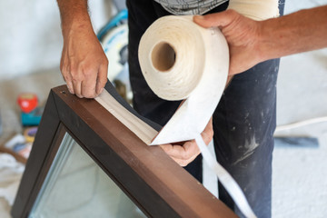 Man glue special tape on plastic window frame