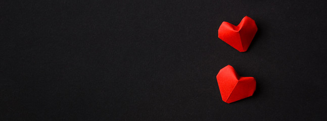 two red heart right in a row on black background. copy space. minimalism. elongated format