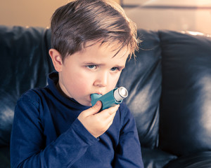 portrait of little boy with asthma inhaler