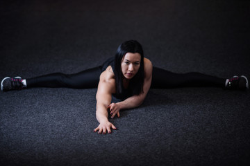 Fototapeta na wymiar athletic woman doing splits in the gym. Woman doing yoga