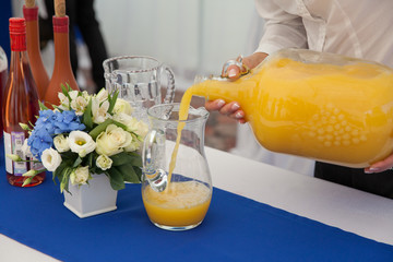 Girl pours juice into a glass jar.