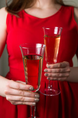 Valentines day romance, beautiful woman in red dress holding champagne glasses in hands,close up.