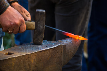 blacksmith performs the forging of hot glowing metal on the anvil