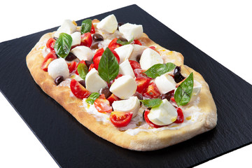 Pizza italiana con pomodorini, mozzarelline e basilico su un tagliere nero