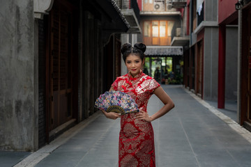 Fototapeta na wymiar Portrait images pretty Chinese girl Wearing a red Cheongsam dress Holding a Folding fan Welcome Chinese New Year Festival.