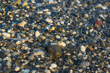 pebble stones on the sea beach, the rolling waves of the sea with foam