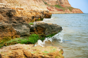 beautiful sea landscape, closeup of stone on the beach, sea coast with high hills, wild nature