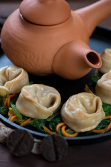 Close-up of steamed dumplings with seaweed and carrot salad and tea, selective focus, vertical shot
