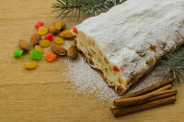 Christmas stollen on darkfestive background with fir twigs, lights and and berries. Close-up on this traditional German dessert