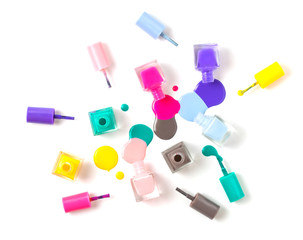 group of three colorful nail polish bottles on spilled paint