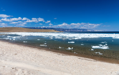 Baikal Lake in sunny May day. Olkhon Island.  White ice floats floating on the blue water of the shallow Elga  Bay of Small Sea Strait. Beautiful spring landscape