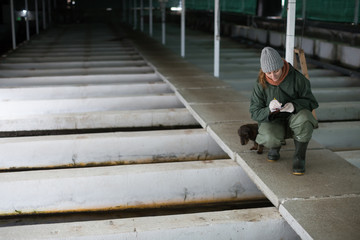 Woman with notebook inspecting fish tanks on farm