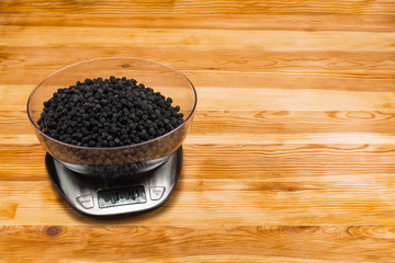 Dry blackberry in bowl on an electronic scale on a wood background with copy space