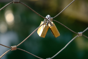 Fototapeta na wymiar Two connected love locks at a bridge railing with blurred background