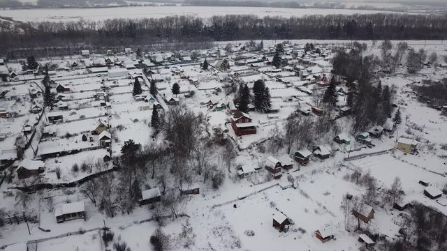 Aerial photography. Winter. Village. The kopter rises up at a 45 degree angle. In the center of the frame is a beautiful wooden house.