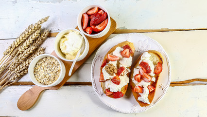 Healthy breakfast ingredients. Homemade oatmeal, yogurt, strawberries on white wooden background, top view, copy space