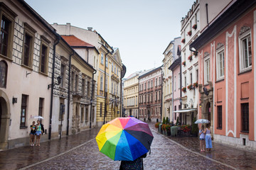 Young and happy woman tourist walking in the rain on streets of old european city Krakow, Poland. Travels around the Europe