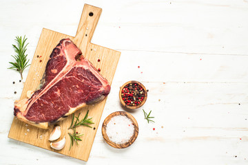 T-bone beef steak on white with spices. 