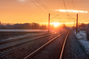 Fototapeta na wymiar Railroad tracks at sunrise in winter. Travel context. Industrial landscape.