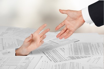 Person under crumpled pile of papers with hand holding a give up
