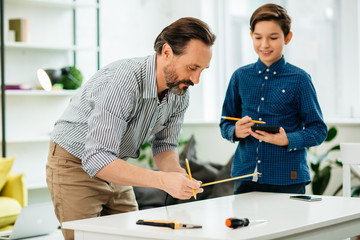 Curious engineer measuring the table and his son looking at it
