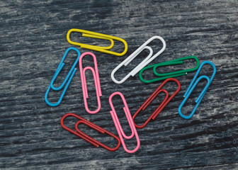 multicolored paper clips on a wooden table, blank for designers 