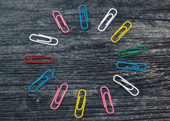 multicolored paper clips on a wooden table, blank for designers 