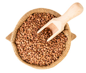 Buckwheat in a bag with a wooden spoon on a white. Isolated.