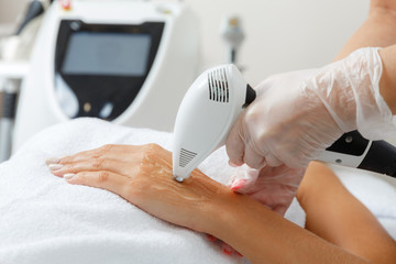 Cosmetologist  perfoms professional IPL cosmetology procedure on hands.