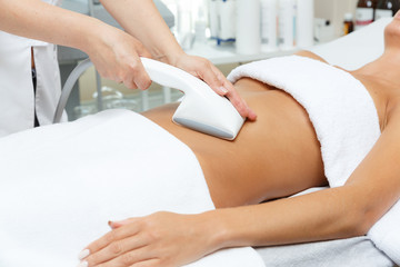 Cosmetologist performs vacuum roller massage LPG of abdomen  in the beauty salon