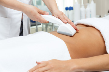 Cosmetologist performs vacuum roller massage LPG of abdomen  in the beauty salon
