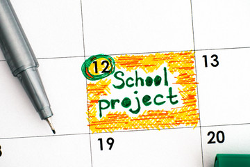 Reminder School Project in calendar with green pen.