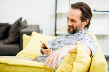 Fototapeta premium Relaxed man using smartphone while sitting at home