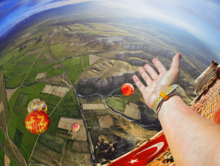 Fototapeta premium Closeup view of a hand of a person in sky . Colorful hot air balloon flying over rock landscape in blue sky at Cappadocia Turkey