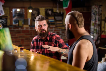 Friends relaxing in bar or pub. Soulmates drunk conversation. Hipster brutal bearded man spend leisure with friend at bar counter. Men relaxing at bar. Strong alcohol drinks. Friday relaxation in bar