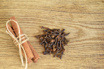 Close up of Christmas spices. Cinnamon sticks and cloves on old wood background. Top view.