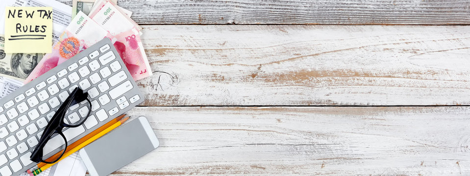 Income tax forms with new changes plus foreign currency on white rustic desk