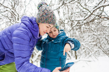 A woman takes a selfie with her son on a winter walk.