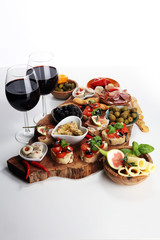 Italian antipasti wine snacks set. Cheese variety, Mediterranean olives, pickles, Prosciutto di Parma, tomatoes, artichokes and wine in glasses