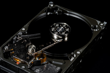 Disassembled and opened hard disk drive, inside view with reflections, isolated on black