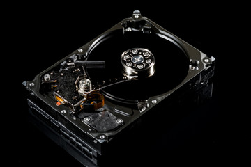 Disassembled and opened hard disk drive, inside view with reflections, isolated on black