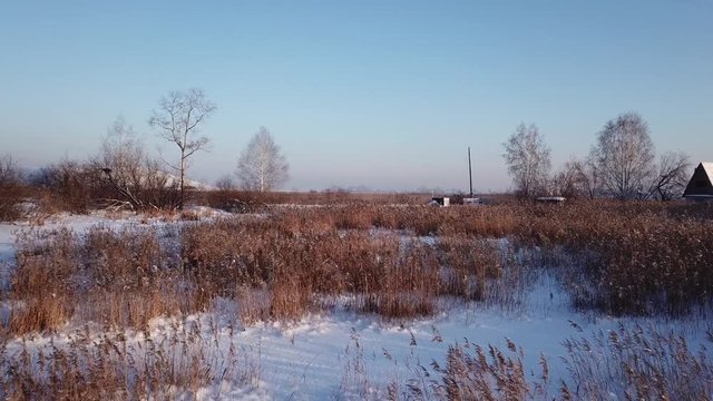 4k aerial photography. Winter landscape with a view of the frozen river. Shrubs. Warm sunset light.